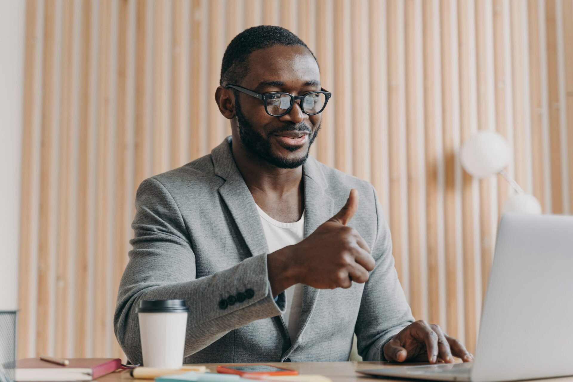 Happy young african american businessman talks online on laptop with client or business partner